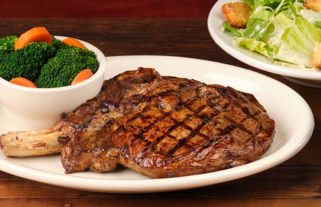 one plate of green salad and one cup of other green with grilled steak of meat in texas roadhouse hand-cut menu