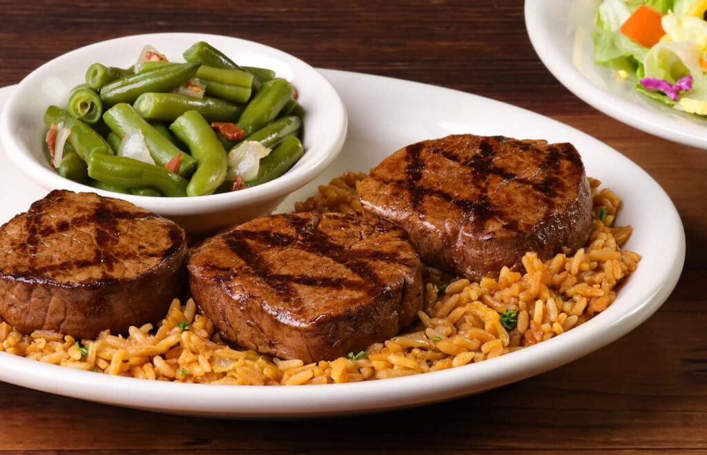 square shape of 3 grilled meat filet and greens with rice